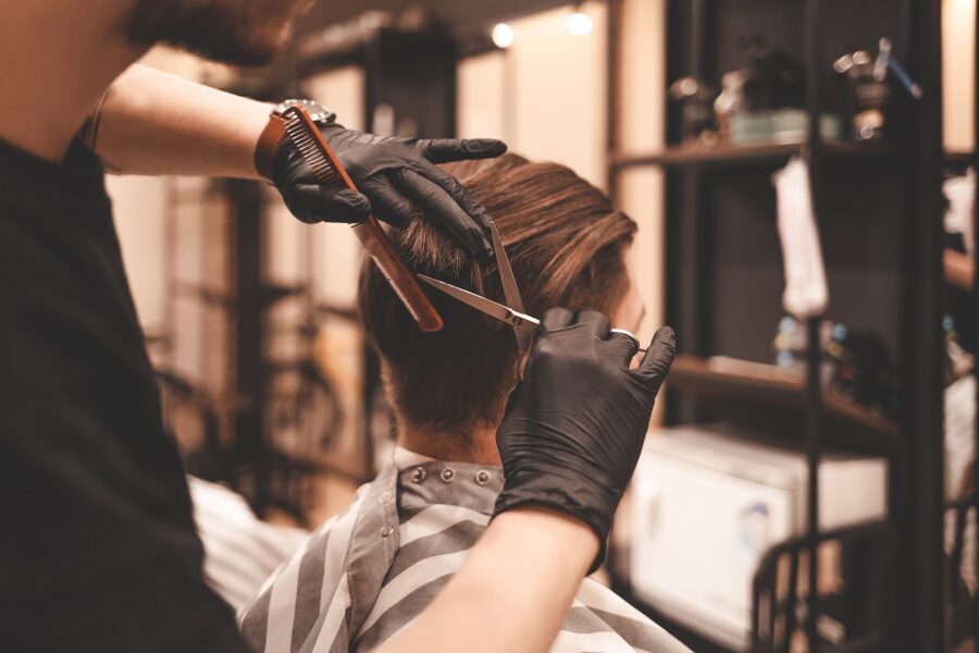 Man hairdresser doing scissors haircut to client.