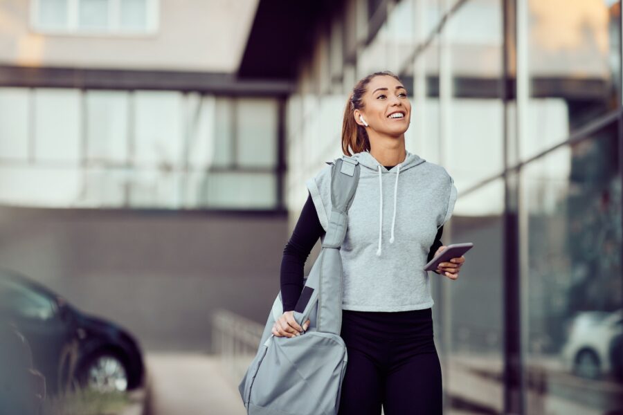 Young happy female athlete going to sports training at gym.