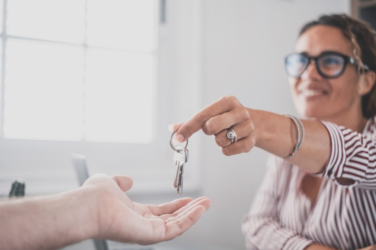 Focus on bunch of keys from house flat apartment in hand of smiling female. Blurred portrait