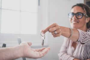 Focus on bunch of keys from house flat apartment in hand of smiling female. Blurred portrait